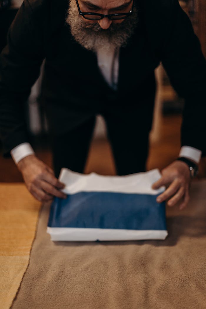 The Art of Drawing Readers In: Your attractive post title goes here Orthodox Jewish man carefully folding a national flag indoors, symbolizing tradition.